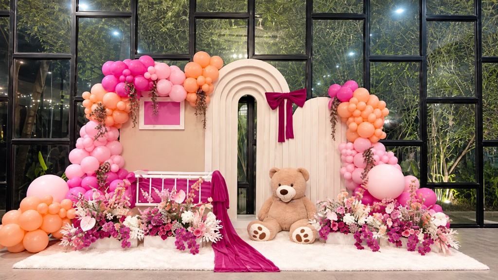 BBMix backdrop with pink and peach garlands, a baby crib, florals and a teddy bear.