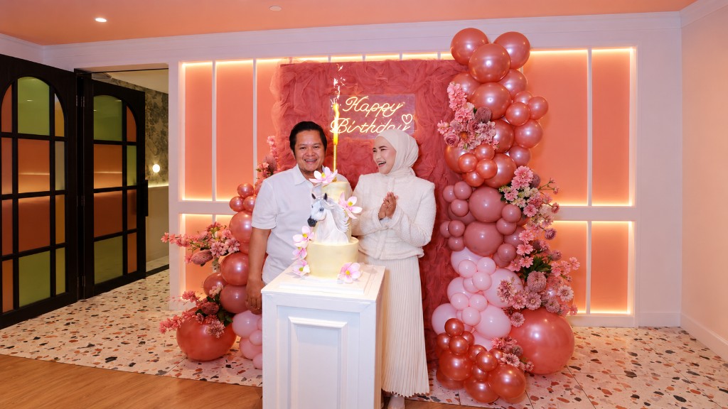 Pink fairytale first-birthday styling with organic balloon garlands, a castle cake and a neon Happy Birthday wall.